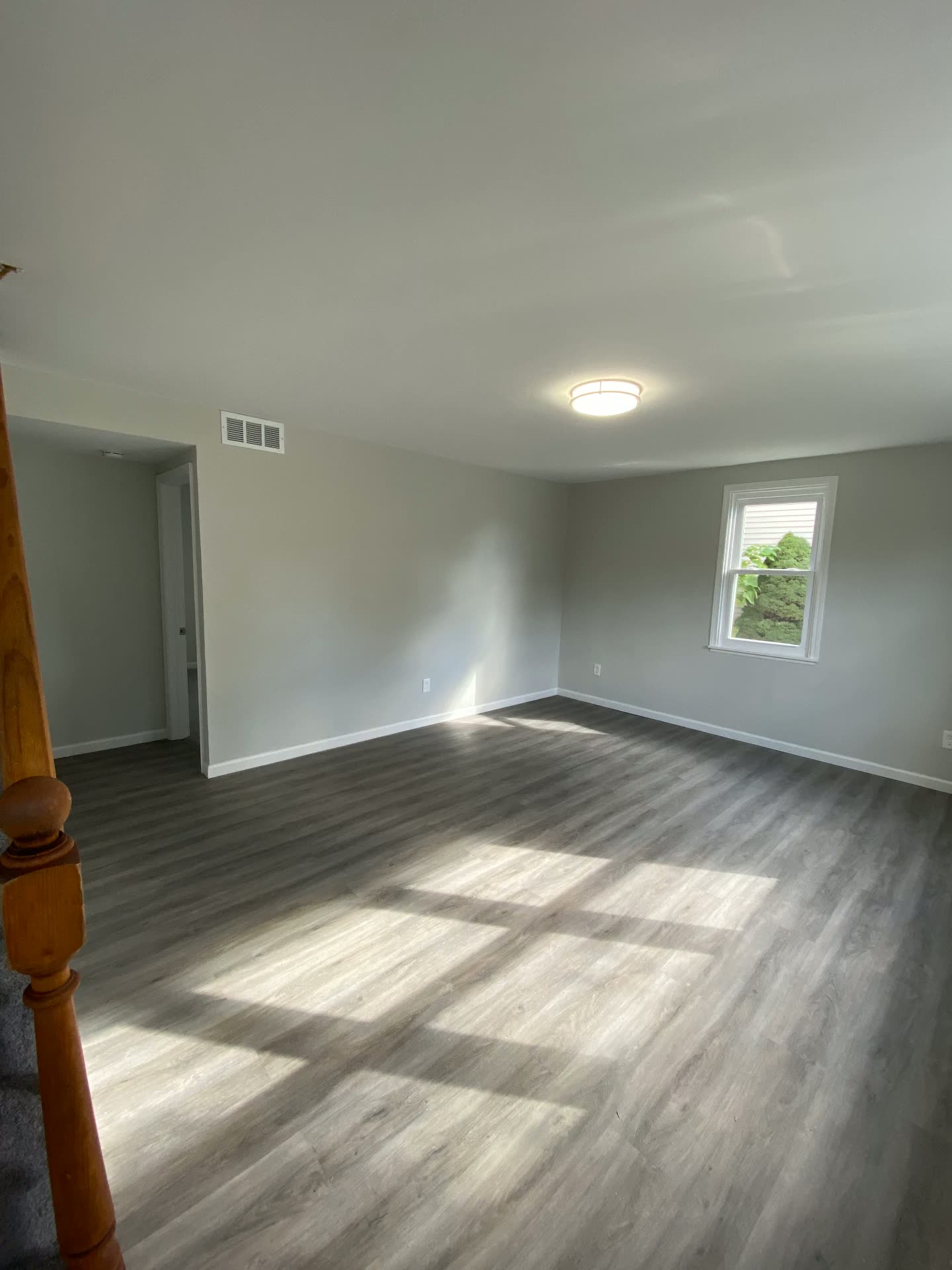 Sala amplia con piso nuevo tipo madera y paredes pintadas