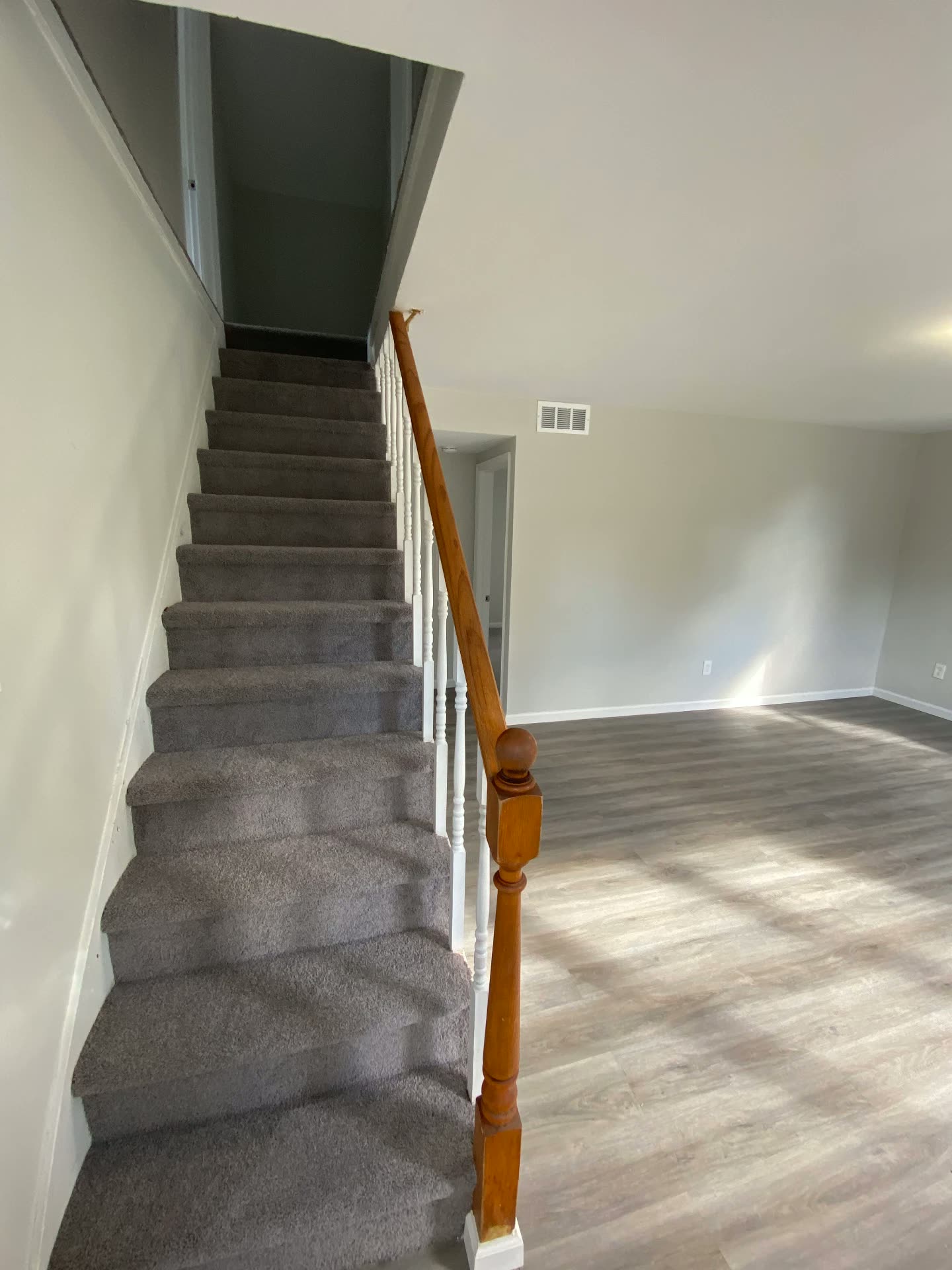 Escaleras con alfombra nueva y barandas pintadas junto a la sala